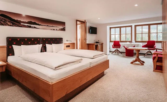 Großes Doppelbett mit Holzrahmen und gepolstertem Kopfteil, daneben Nachttische
