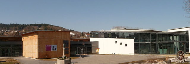 Außenansicht des Glasmuseums Frauenau mit verglaster Fassade und Vorplatz.