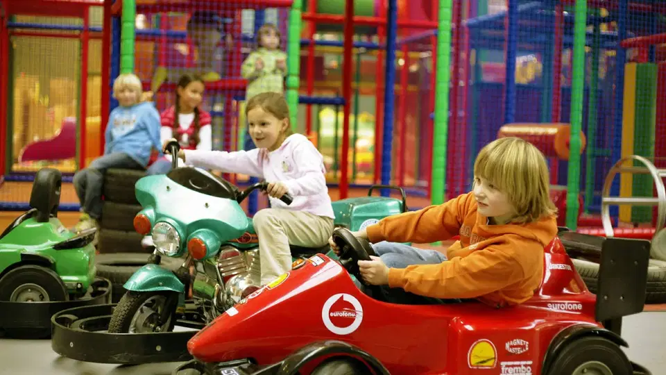Kinder fahren Elektroautos im Indoor-Spielplatz