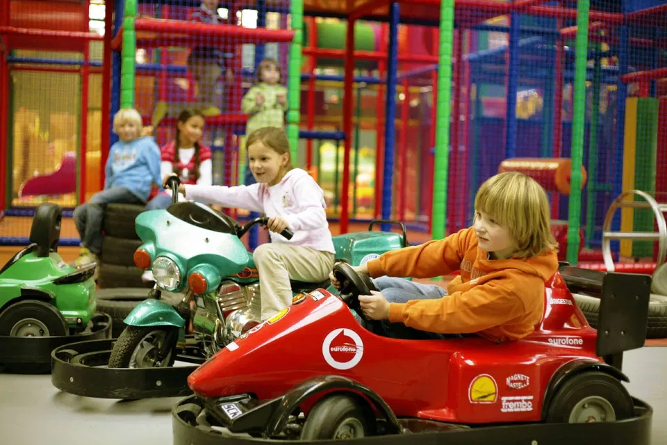 Kinder fahren Elektroautos im Indoor-Spielplatz