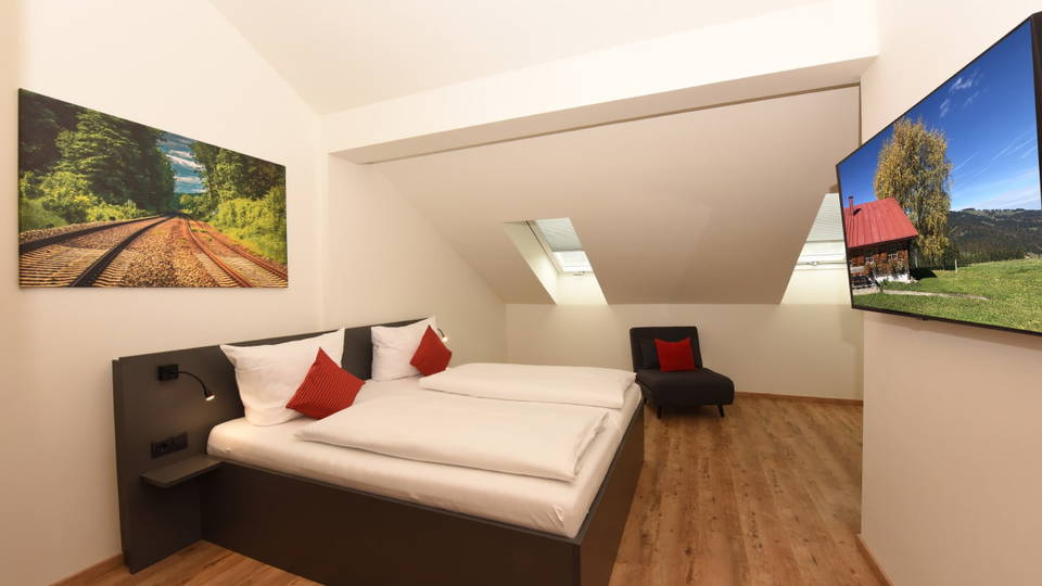 Doppelzimmer large mit roten Kissen und zusätzlichem Schlafsessel
