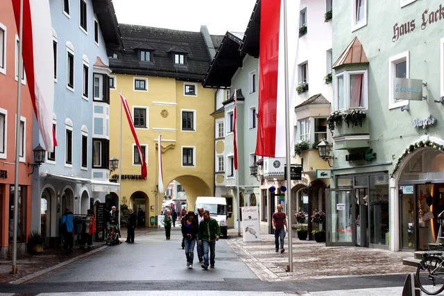 Straße in farbenfroher Altstadt mit Bogendurchgang, bunten Gebäuden und roten Flaggen.