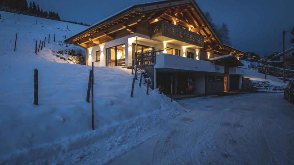 Beleuchtetes Chalet Steinbock im Schnee am Hang