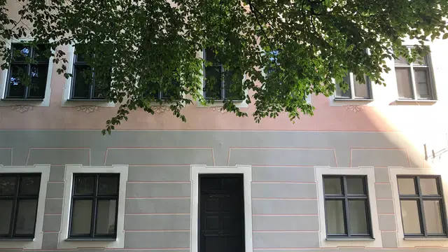 Historische Fassade des Stadtmuseums Kaufbeuren mit Eingangstür und Baumkrone im Vordergrund. Ortsmotiv zur Ausflugsplanung.