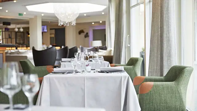 Elegantes Restaurant mit weißen Tischdecken, Gläsern und modernen Stühlen