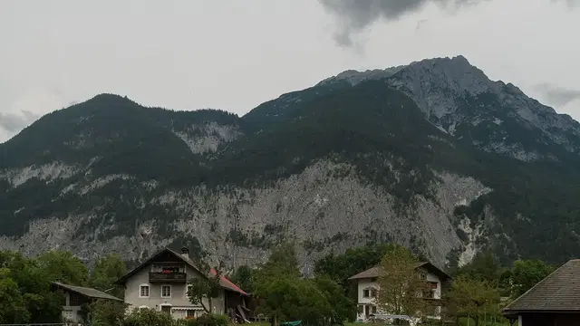 Häuser in Nassereith vor bewaldeten und felsigen Bergen.