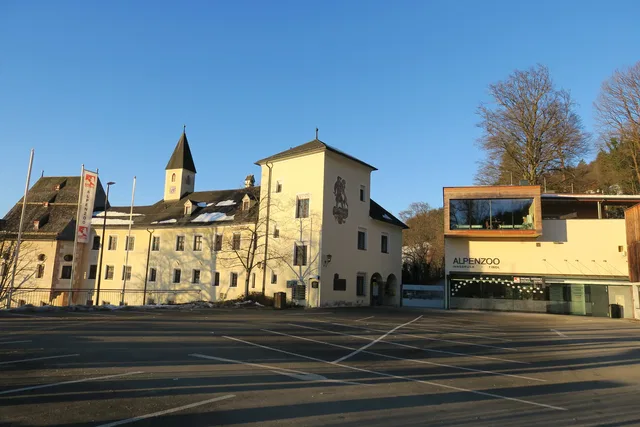Eingangsbereich des Alpenzoos Innsbruck mit historischen Gebäuden und Parkplatz