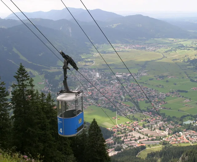 Blaue Berggondelbahn-Kabine Nummer 4 schwebt über Wald und Tal.
