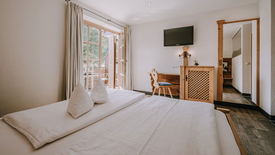 Doppelbett, Fernseher und Balkontür im Zimmer Enzian.