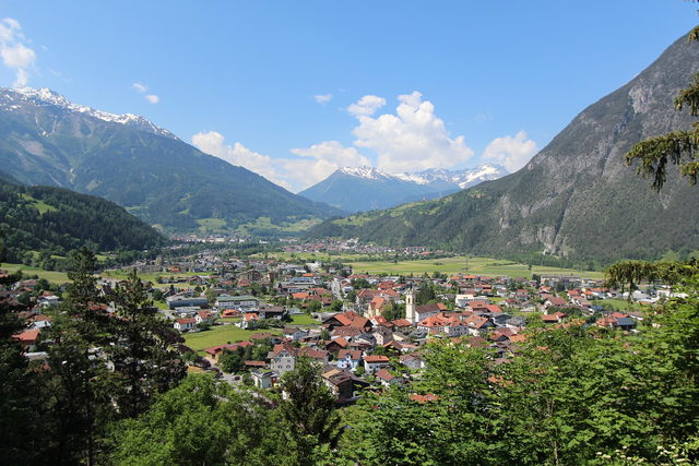 Ortsansicht von Zams mit Kirche und dem Inntal zwischen grünen Berghängen