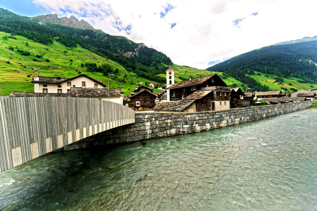 Dorfbrücke über den Valserrhein mit Steindächern und Kirche in Vals