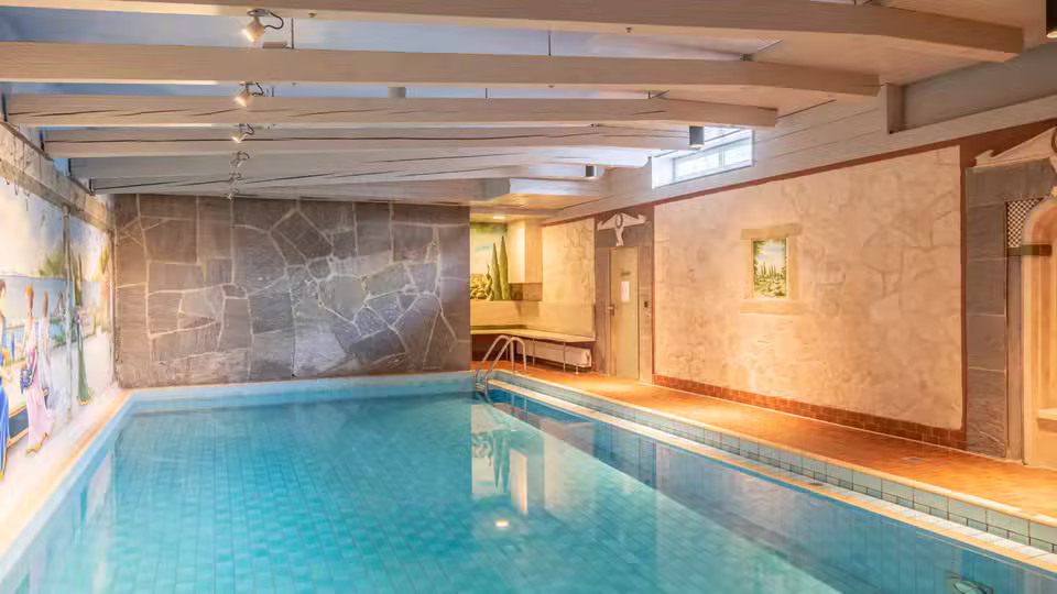 Innenpool mit Natursteinwänden und Zugang zum Saunabereich
