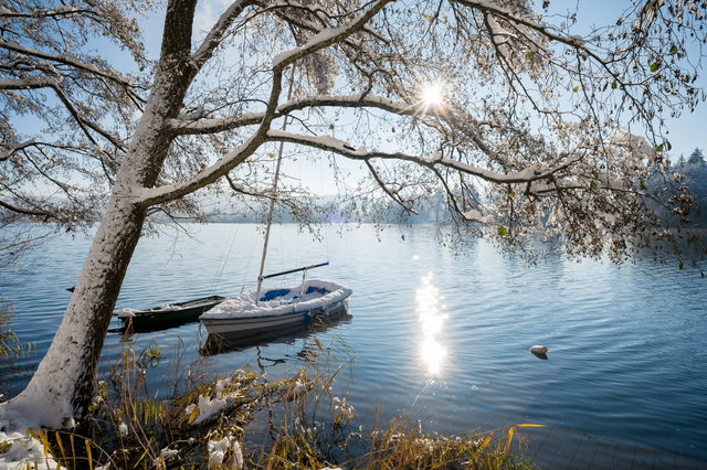 Schneebedecktes Boot am winterlichen Ufer des Illmensees