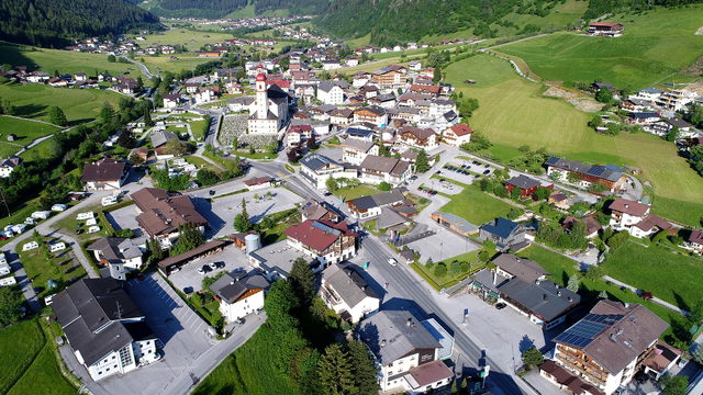 Blick von oben auf Neustift im Stubaital mit Kirche und grünen Hängen