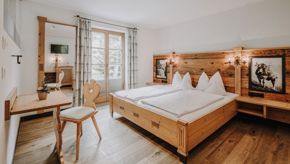 Doppelbett, Tisch und Terrassentür im Zimmer Alpenrose.