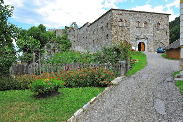 Außenansicht der Klosterruine Arnoldstein mit Garten und Zufahrtsweg
