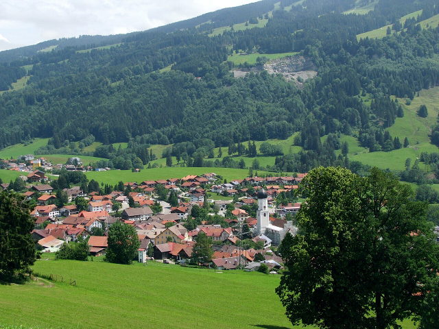 Blick auf Rettenberg mit Kirche und grünen Hängen am Grünten