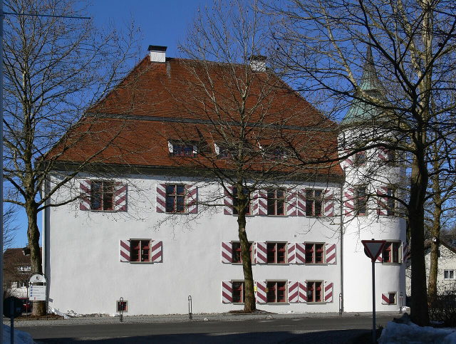 Das Alte Schloss in Amtzell mit weißer Fassade, rot-weißen Fensterläden und großem Ziegeldach
