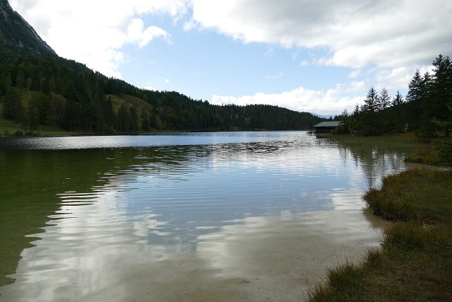 Ruhiges Wasser des Ferchensees mit bewaldeten Berghängen und Ufergebäude