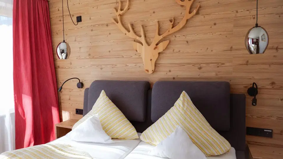 Doppelzimmer mit großem Bett, Holzwand und rotem Vorhang
