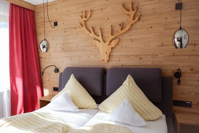 Doppelzimmer mit großem Bett, Holzwand und rotem Vorhang