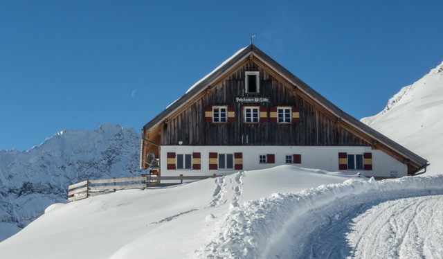 Potsdamer Hütte im verschneiten Fotschertal vor blauem Himmel
