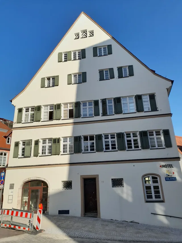 Historisches Gebäude mit grünen Fensterläden und Schild „Hotel Milano“