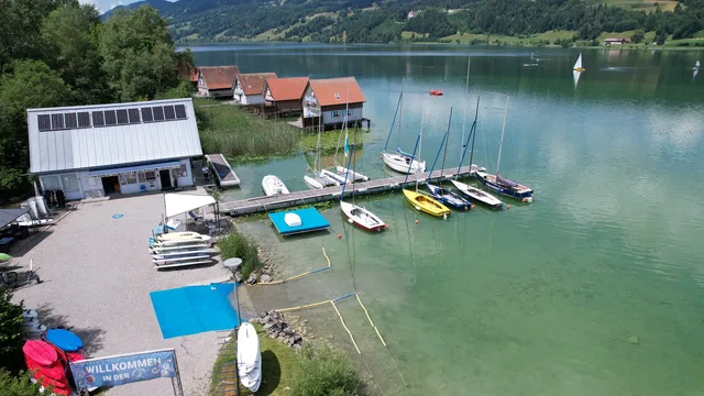 Bootssteg am See mit Booten und Häusern am Ufer