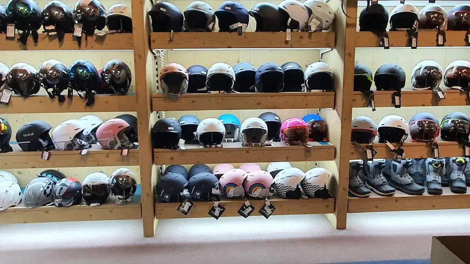 Viele Helme in unterschiedlichen Farben ordentlich auf Holzregalen.