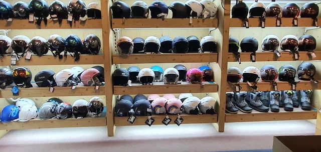 Viele Helme in unterschiedlichen Farben ordentlich auf Holzregalen.