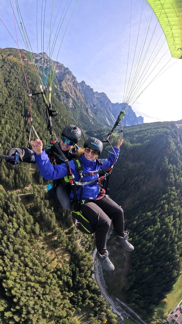 Tandem-Paragleitflug mit Pilot und Passagierin über einem Tiroler Bergtal
