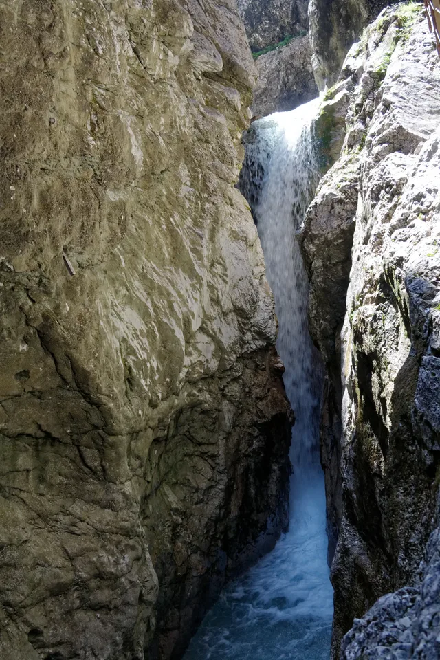 Enge Felsschlucht mit einem schmalen Wasserfall zwischen rauen Felswänden.