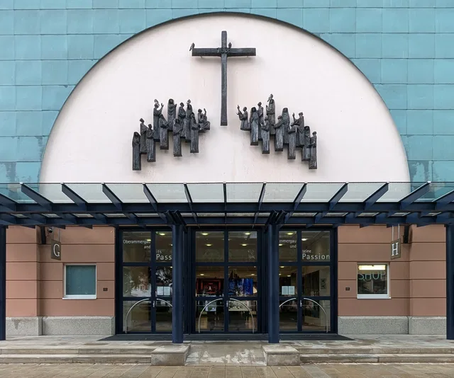 Eingangsbereich des Passionstheaters Oberammergau mit Bronzerelief und Glasvordach.