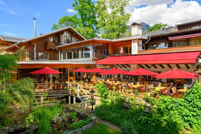Restaurantgebäude und Sonnenterrasse am grünen Kräutergarten