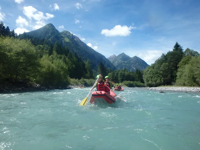 Zwei Paddler im roten Schlauchcanadier vor einer Bergkulisse
