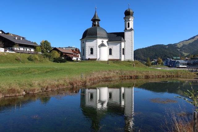 Seekirchl in Seefeld mit Spiegelung im Raabach und grünen Wiesen