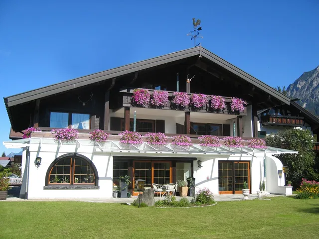 Außenansicht des Landhauses Gerlach mit blumengeschmückten Südbalkonen und Garten.