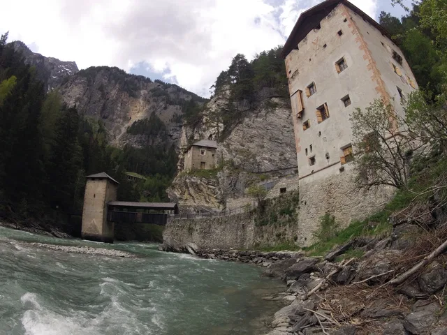 Fluss fließt durch Schlucht, neben historischen Gebäuden an Felswand und Brücke