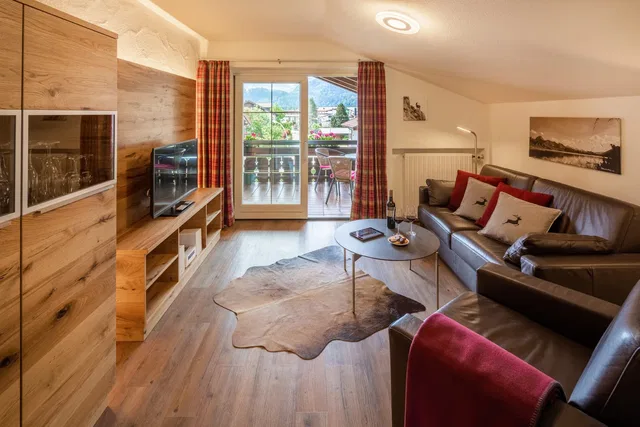 Wohnzimmer mit Ledersofas, Holzmöbeln und Balkontür mit Blick nach draußen