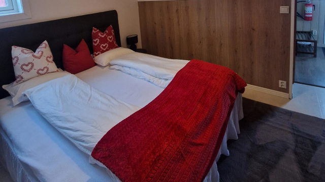 Doppelzimmer bei Lappland Tour mit Holzwand und roter Tagesdecke