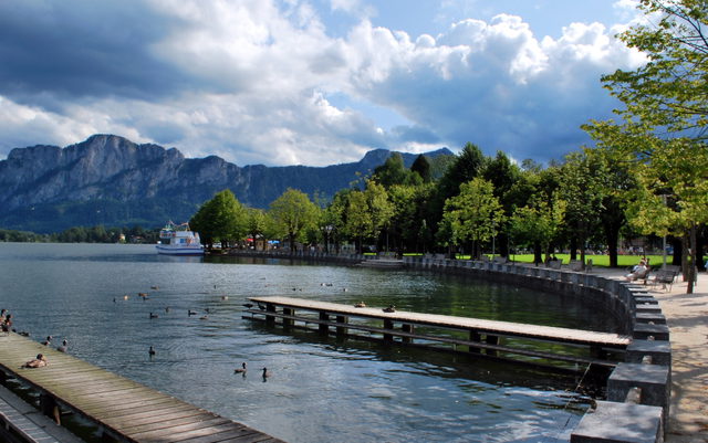 Seepromenade und Baumreihe am Mondsee mit Bergkulisse