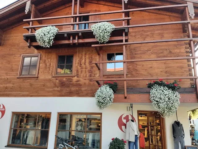 Holzhaus mit Balkonpflanzen und Ladenfront im Erdgeschoss