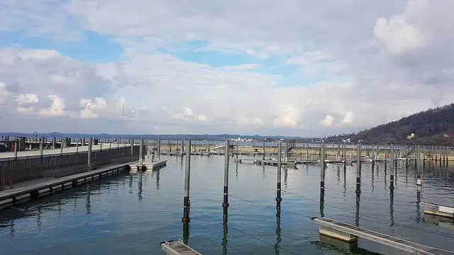 Bootsstege am Bregenzer Bodenseeufer mit Blick über das Wasser und zum Uferhang. Ortsmotiv zur Ausflugsplanung.