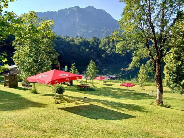 Naturbad Freibergsee mit Liegewiese, Sonnenschirmen, See und Bergkulisse