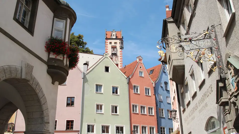 Bunte Fassaden historischer Häuser in Füssen Lechhalde, Turm im Hintergrund.