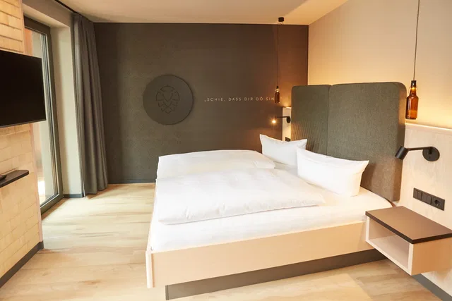 Doppelbett mit gepolstertem Kopfteil im Hotel Zum Goldenen Hirsch.