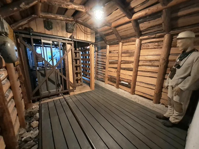 Nachbildung eines Bergwerksstollens mit Holzbalken, Geländer und einer Bergarbeiterfigur.