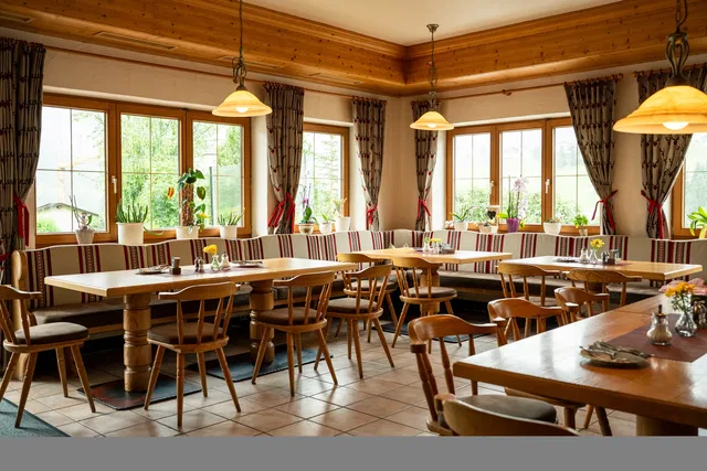 Gemütliches Restaurant mit Holztischen, Stühlen und großen Fenstern.