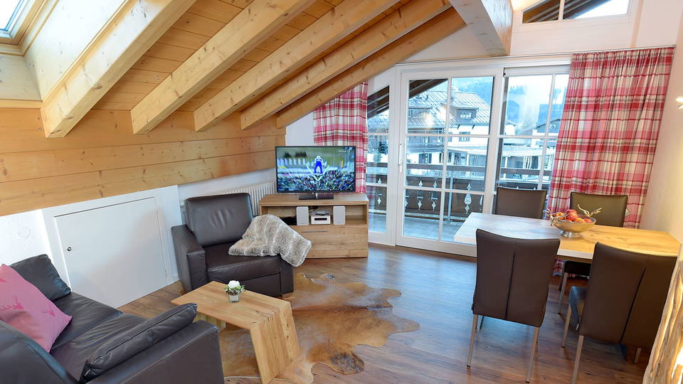 Wohnbereich der Ferienwohnung Nebelhorn unter der Dachschräge mit Essplatz und Balkontür.
