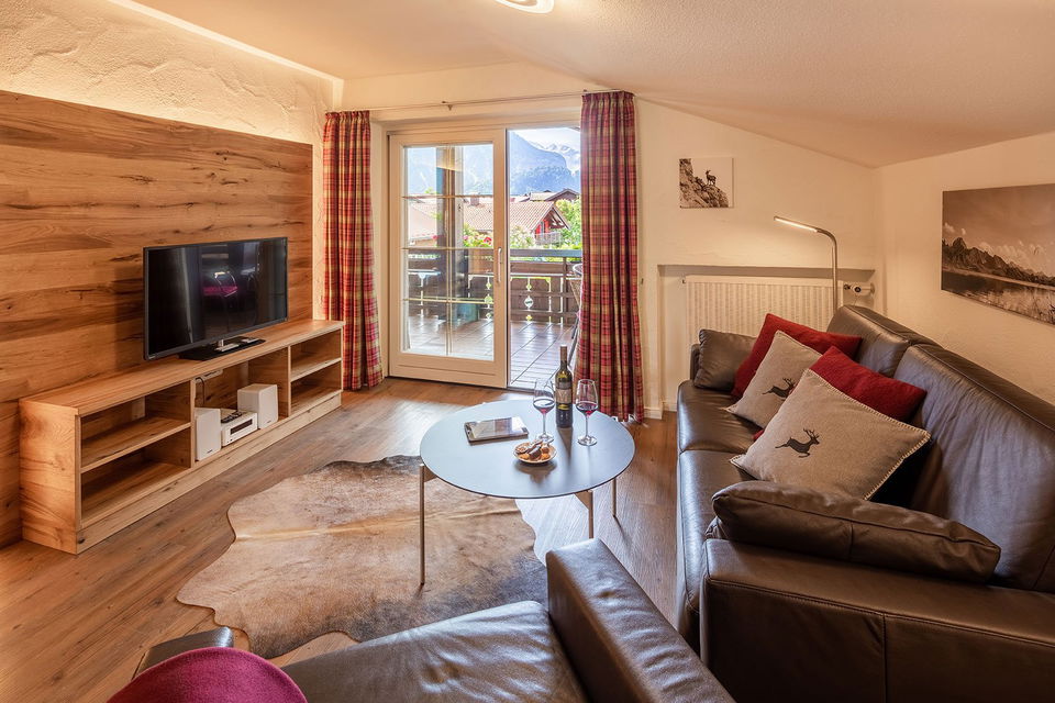 Wohnzimmer der Ferienwohnung Himmelschrofen mit Ledersofa und Zugang zum Südbalkon.